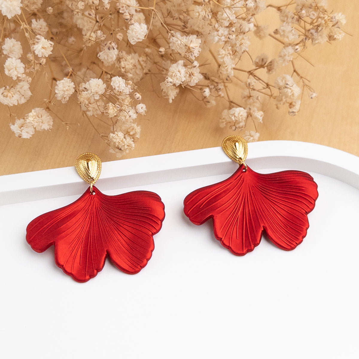 Boucles d'oreilles Julianna posées, feuille de ginkgo rouge satinée sous une goutte dorée